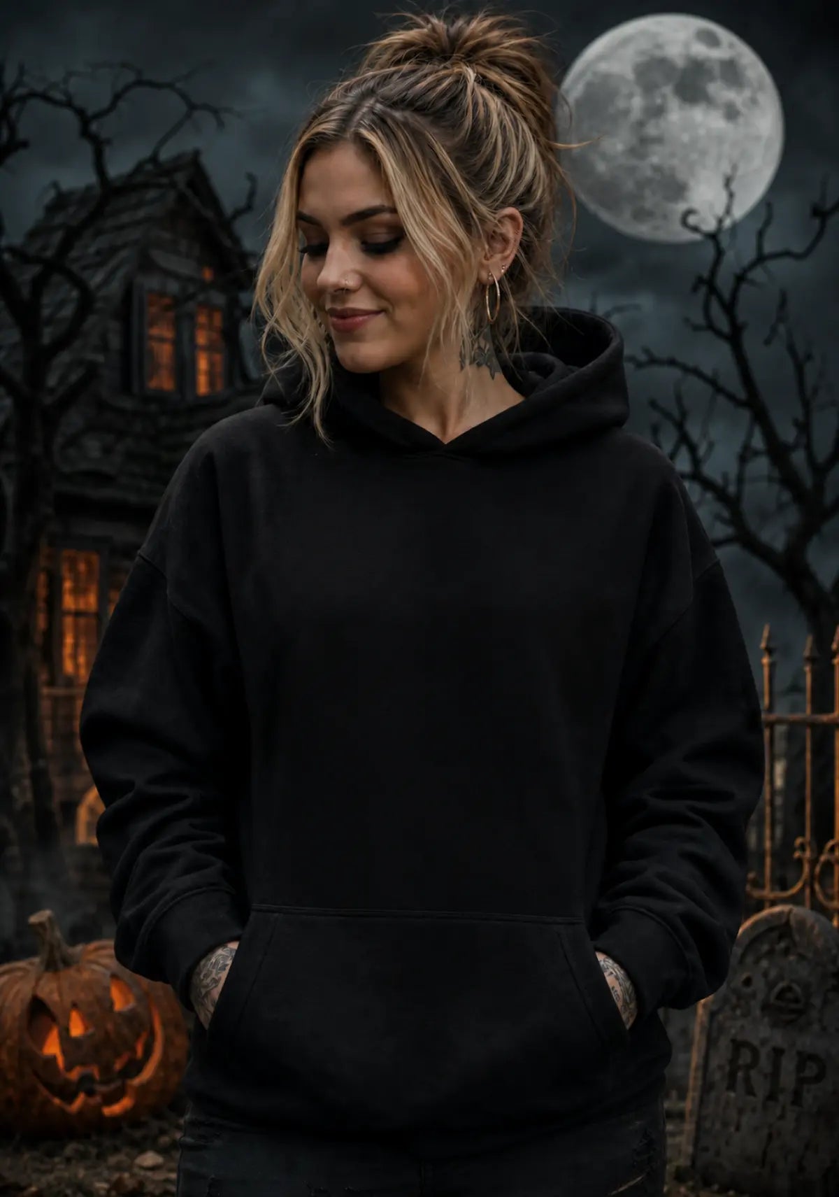 Person wearing a black hoodie in a spooky Halloween scene with a gothic house, full moon, jack‑o’-lantern and gravestone