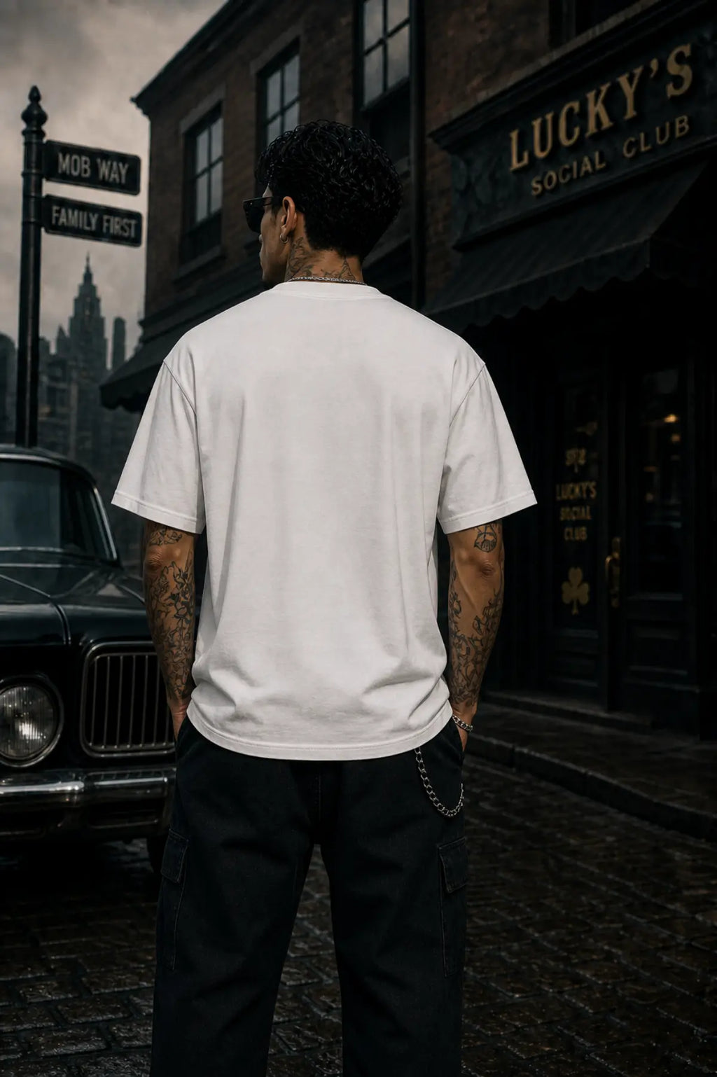 A man seen from behind in a white T‑shirt and black pants standing on a city street before a brick building with a Lucky’s Social Club sign.
