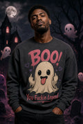 Person in dark sweatshirt with playful ghost graphic standing before haunted house backdrop with moon and floating cartoon ghosts