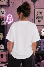 Person facing away in a pastel spooky room wearing an oversized white T‑shirt, surrounded by cute ghost décor and neon ghost light