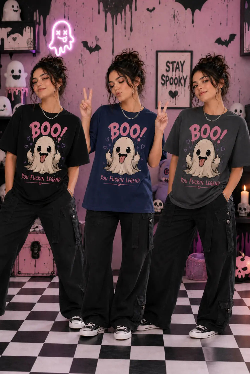 Three people in spooky pastel room wearing ghost‑print tees, posing together amid Halloween décor and neon ghost accents