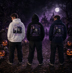 Three people in Halloween forest scene wearing chibi skull‑cat hoodies, standing amid pumpkins, tombstones and purple mist