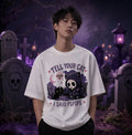 Person in gothic graveyard scene wearing white tee with chibi skeleton‑cat design, standing amid moonlight, tombstones and purple glow