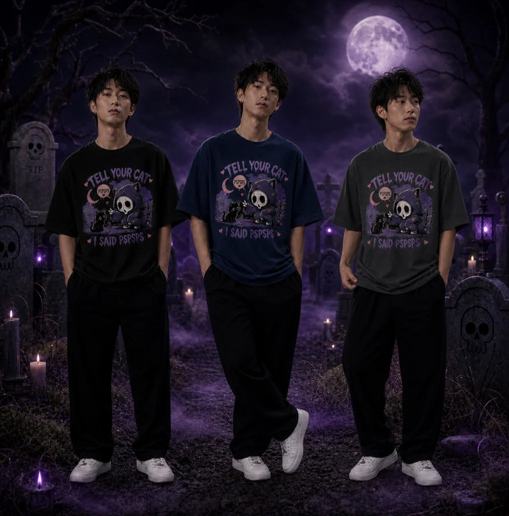 Three people in moonlit graveyard wearing chibi horror tees, standing amid tombstones, skull motifs and eerie purple candle glow