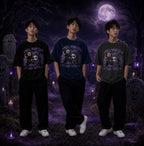 Three people in moonlit graveyard wearing chibi horror tees, standing amid tombstones, skull motifs and eerie purple candle glow