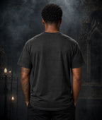 Person in grey T‑shirt facing away in a gothic stone‑arch setting, with candles and moody lighting creating a dark atmospheric scene.