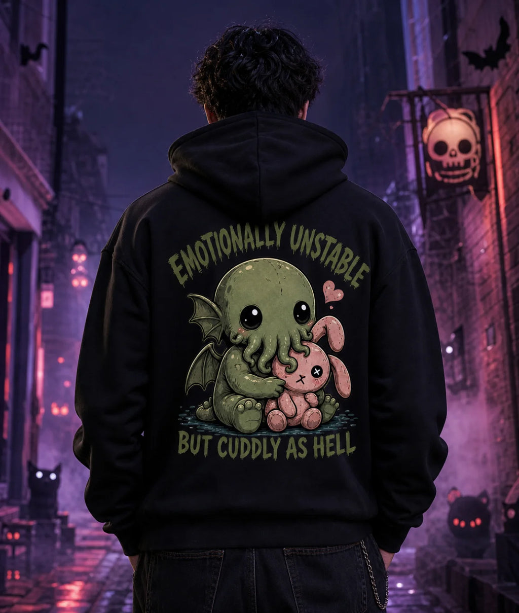 Person in black hoodie with chibi Cthulhu graphic standing in a moody alley lit by purple and blue eerie Halloween lighting.