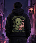 Person in black hoodie with chibi Cthulhu graphic standing in a moody alley lit by purple and blue eerie Halloween lighting.