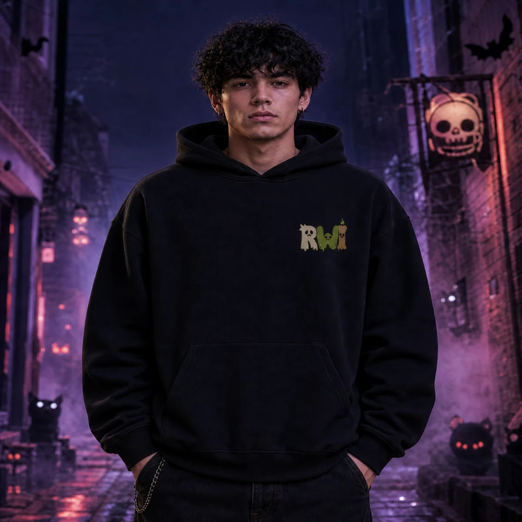 Person in black RWI hoodie standing in a foggy Halloween alley with glowing jack‑o’-lanterns, bats, and eerie orange lighting.