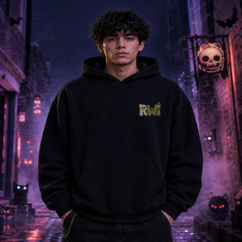 Person in black RWI hoodie standing in a foggy Halloween alley with glowing jack‑o’-lanterns, bats, and eerie orange lighting.