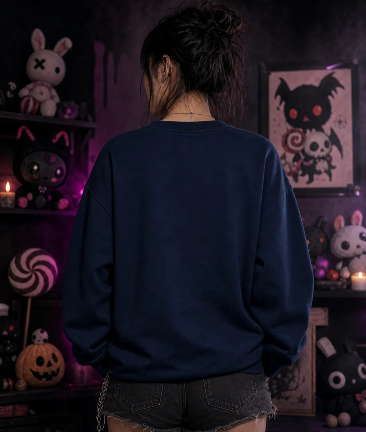 Person in dark blue sweatshirt and denim shorts facing away, surrounded by gothic plush toys, candles, and eerie purple lighting.
