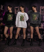 Three people in black, white, and gray Cthulhu sweatshirts standing indoors with gothic plush toys, pumpkins, and spooky décor.