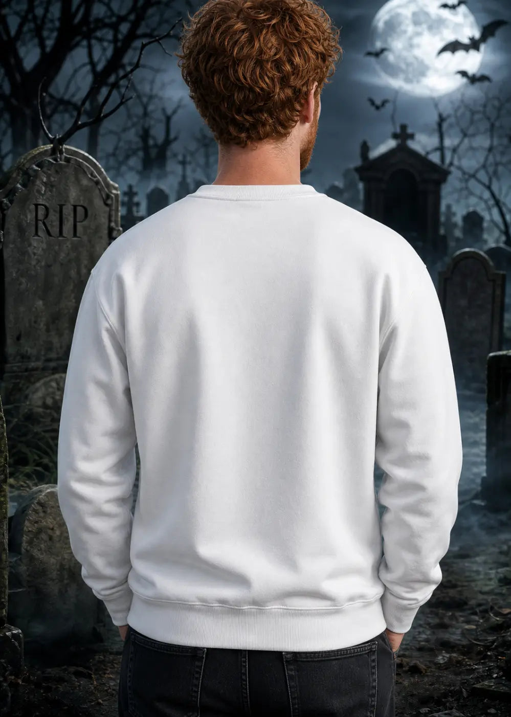 A man stands in a moonlit graveyard wearing a plain white sweatshirt, surrounded by tombstones and eerie night fog.