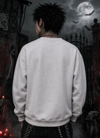Person facing away in gothic scene wearing light sweatshirt, standing before moonlit gates, red candles, graffiti stone and bats