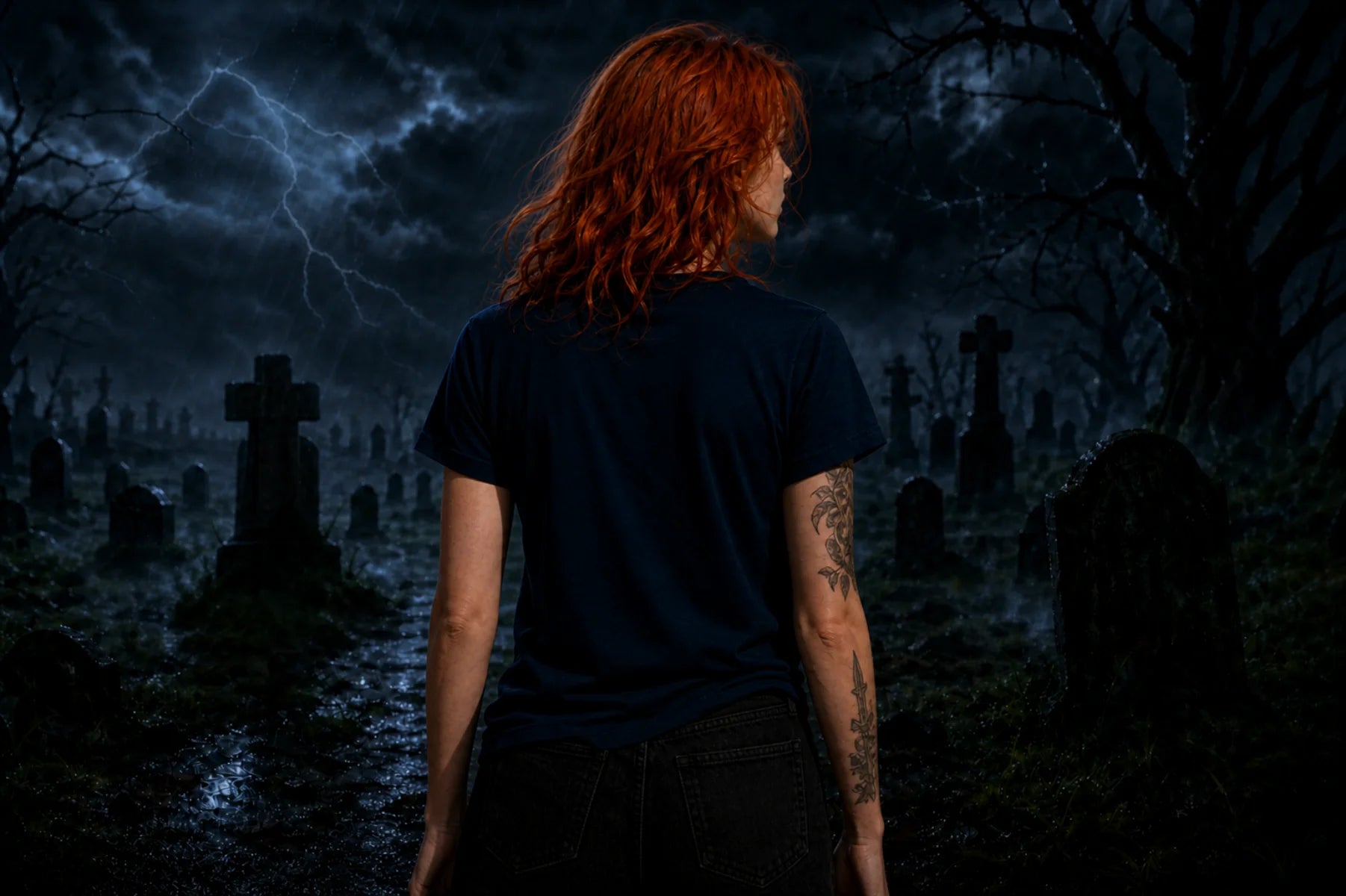 A red‑haired person seen from behind stands in a spooky graveyard at night wearing a navy shirt under a stormy sky with lightning.