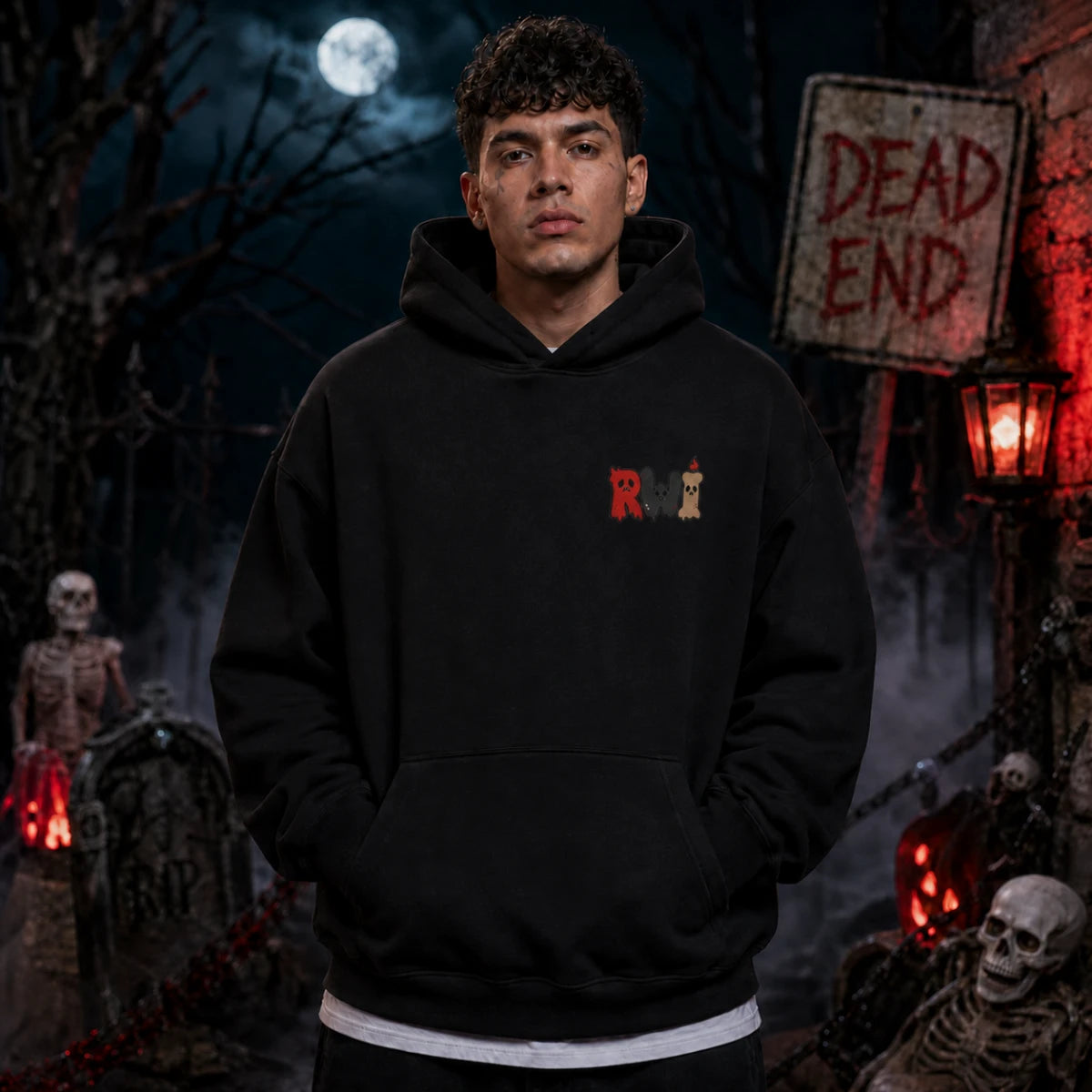 Person wearing a black RWI hoodie in a spooky graveyard scene with skeletons, fog, full moon, tombstones and a red lantern glow