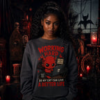Person wearing a dark sweatshirt with a red devil cat‑lover design in a gothic room with skulls, candles, ornate furniture and red light