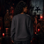 Person facing away in a gothic room with red candles, skull décor and dark furniture while wearing a plain dark sweatshirt
