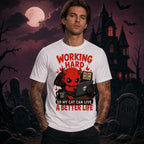 Person wearing a white T‑shirt with a cute red devil cat‑lover design in a spooky Halloween scene with moon, bats and gravestones